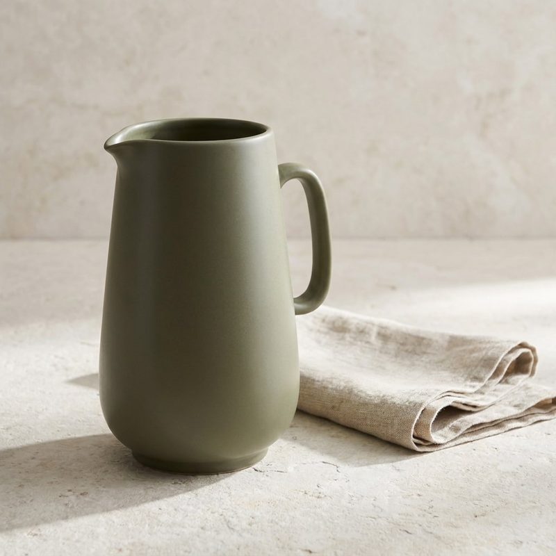 Concept sample: the olive jug on a stone surface beside a folded linen napkin